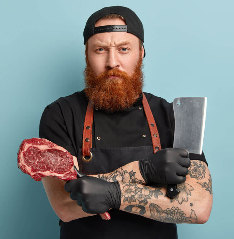 man-with-ginger-beard-apron-gloves-holding-knife-meat